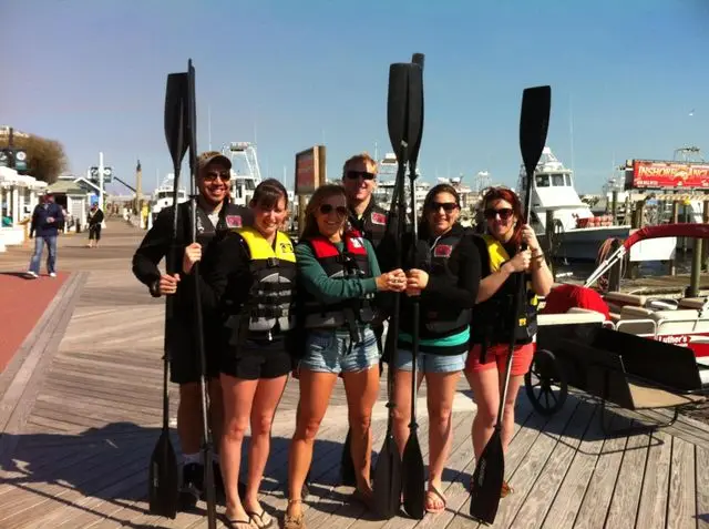 A group carrying paddleboards down to the water