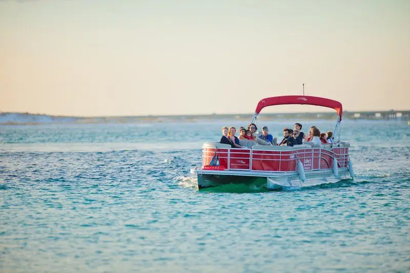 A pontoon boat cruising the bay with a full group aboard