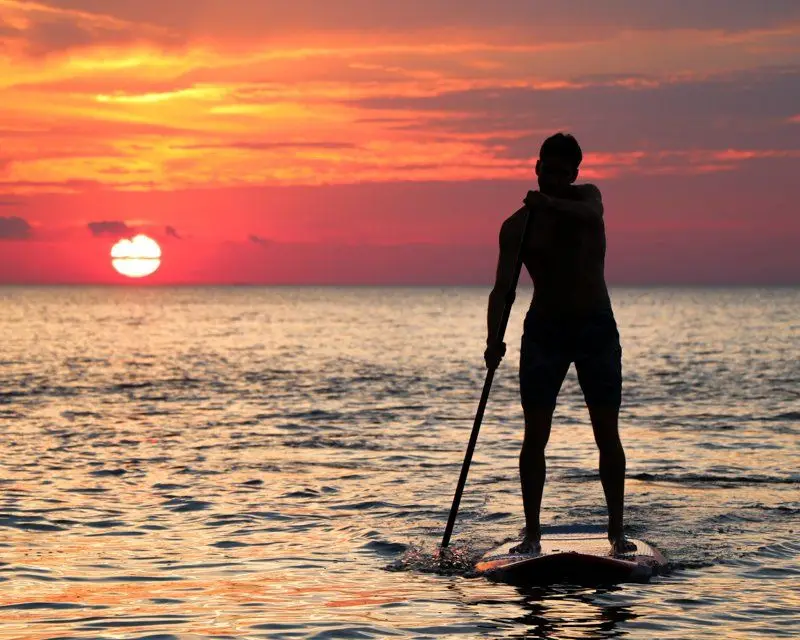 A paddleboarder silhouetted against a Destin sunset